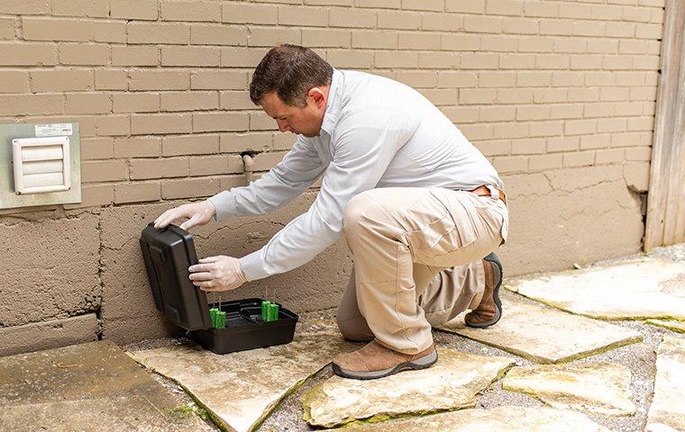 a pest technician inspecting a rodent trap outside of a home in memphis tennessee